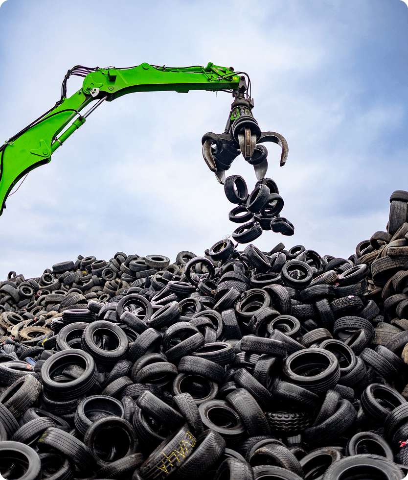 Crane lifting tires at recycling facility.