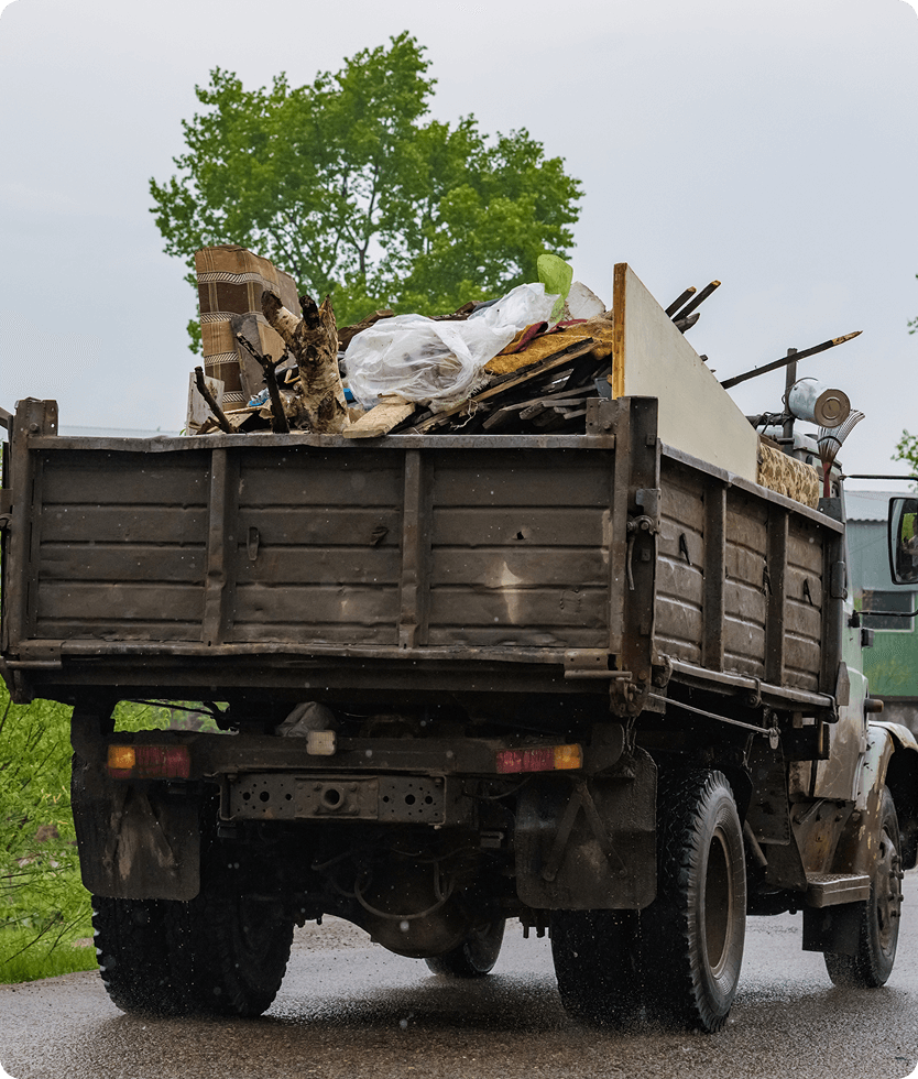 Truck carrying waste materials on road.