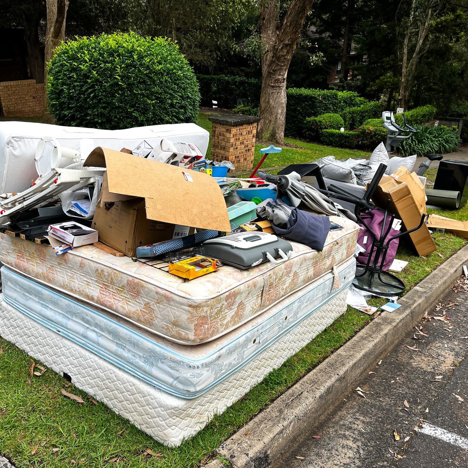 Discarded household items piled on mattresses outdoors.